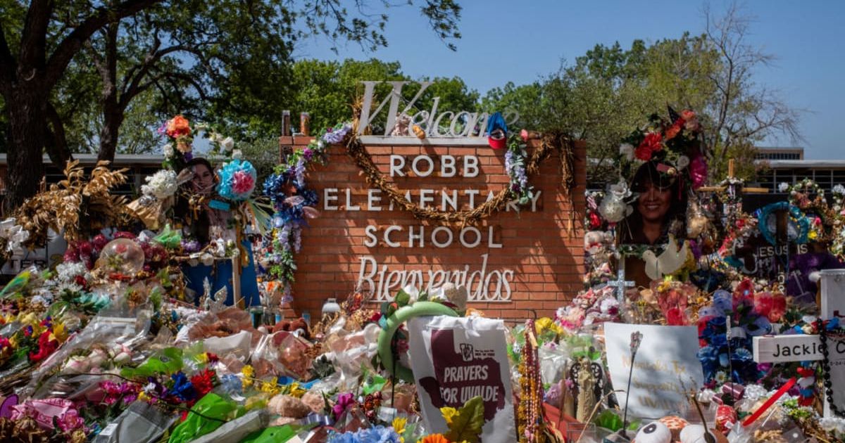 The Robb Elementary School sign is seen covered in flowers and gifts on June 17, 2022 in Uvalde, Texas. (Photo by Brandon Bell/Getty Images)