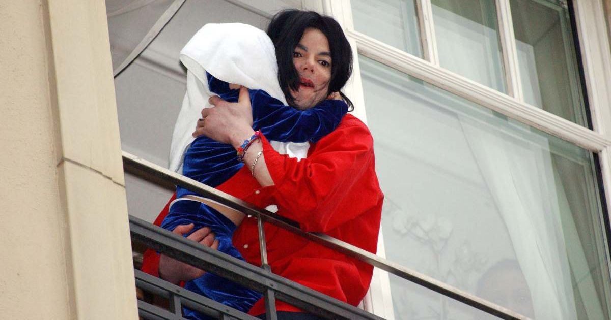 Michael Jackson appears on the balcony of the Adlon Hotel with an unidentified child on November 19, 2002, in Berlin, Germany (Cover Image Source: Getty Images | Photo by Olaf Selchow)