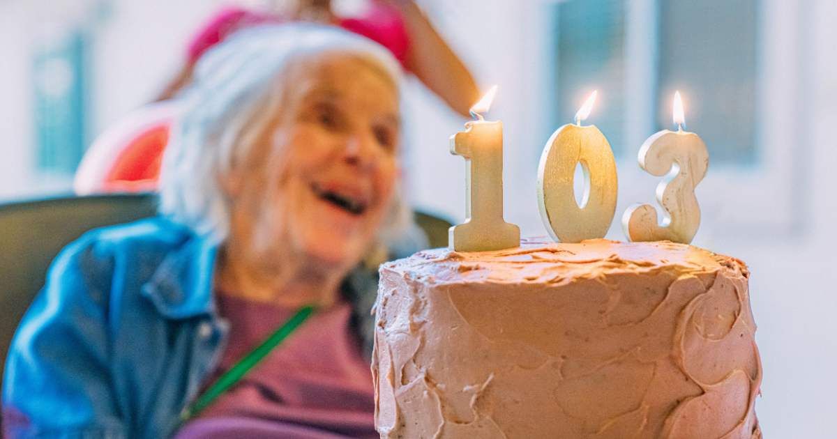 A cheerful elderly woman celebrating her 103rd birthday with her favorite chocolate cake. (Representative Cover Image Source: Getty Images | Photo by Jeremy Poland)