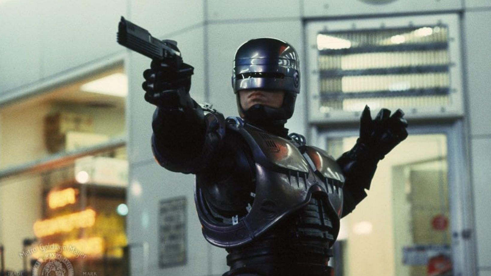 Peter Weller as RoboCop aiming his weapon in the 1987 film ‘RoboCop’ (Image Source: Orion Pictures)