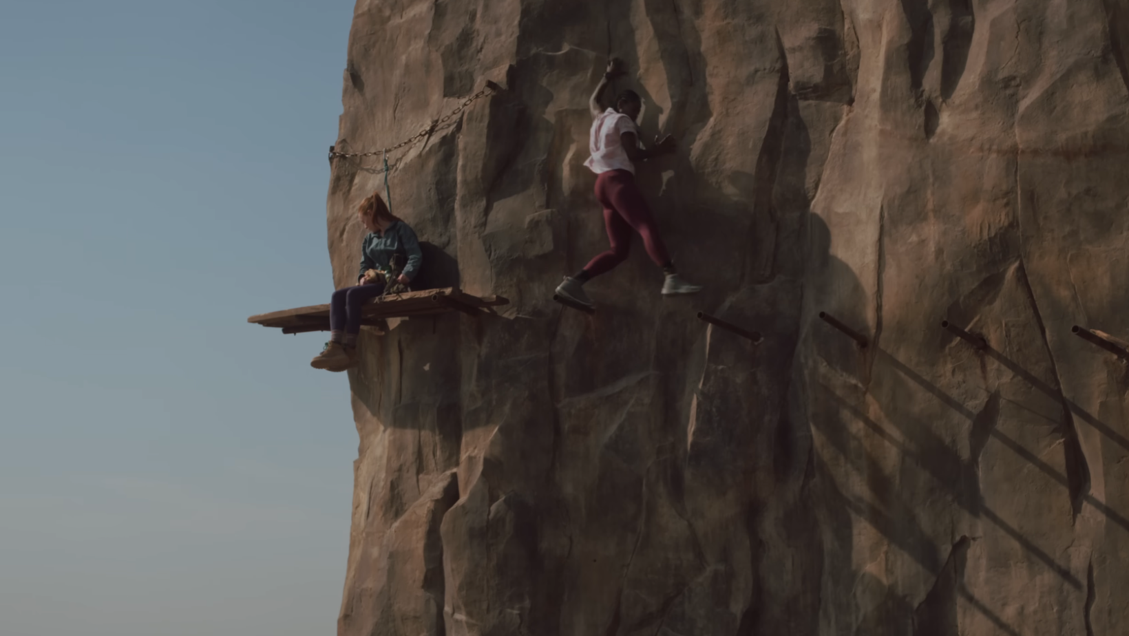 Luce (Arsema Thomas) jumps toward Jax Hunter (Harriet Slater) after their route collapses in ‘Fall 2: Deadpoint’ (Image Source: YouTube | Lionsgate Movies)
