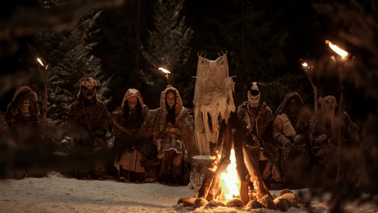 The masked survivors gather around a fire during a wilderness ritual in ‘Yellowjackets’ (Image Source: Paramount+)