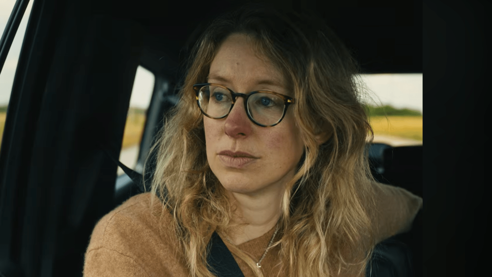 Elizabeth Holmes rides in a car in a still from the trailer of ‘You Can See Everything’ (Image Source: A24).