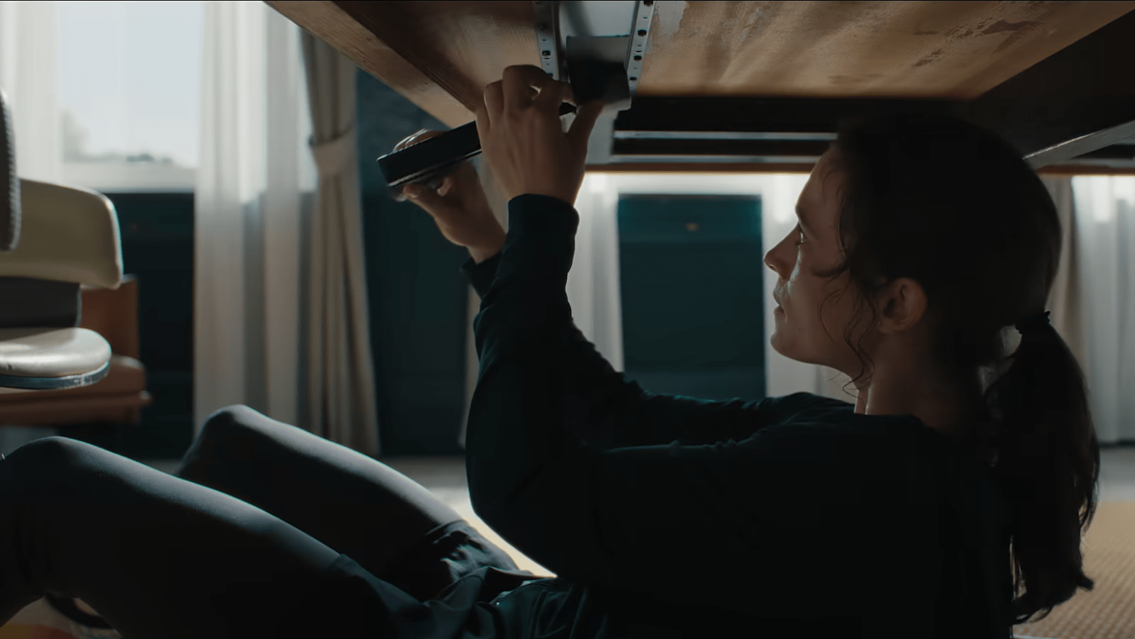 Lisa prepares a hidden handgun beneath the table before confronting Robert Lenzen in ‘The Trap’ (Image Source: Netflix)
